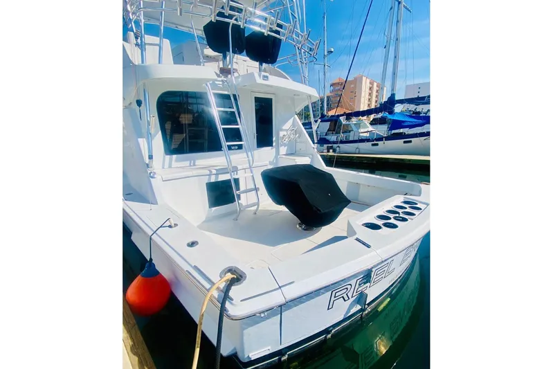  Yacht Photos Pics 2001 Hatteras 60 Convertible yacht docked, featuring a spacious deck and fishing rod holders.