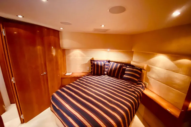  Yacht Photos Pics Luxurious bedroom interior of 2001 Hatteras 60 Convertible yacht with striped bedding.
