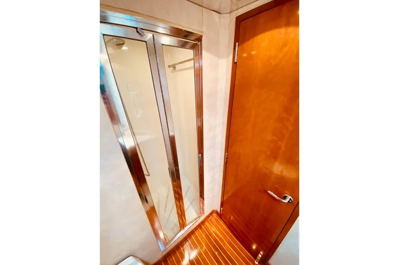  Yacht Photos Pics Bathroom interior of 2001 Hatteras 60 Convertible yacht with wooden door and glass shower.