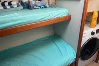 Bunk beds with teal sheets in a 1999 Viking 58 EB yacht cabin, adjacent to a washing machine.