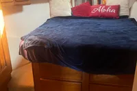 Cozy bedroom in 1999 Viking 58 EB yacht with plush bedding and "Aloha" pillow.