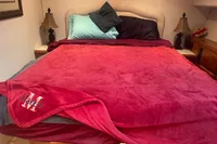 Cozy bedroom with red blanket, colorful pillows, and bedside lamps in a 1999 Viking 58 EB.