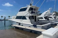1999 Viking 58 EB yacht docked at marina under clear blue sky.