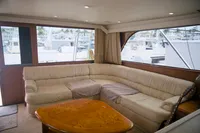 Interior of a 1999 Viking 58 yacht with beige sectional sofa and wooden table.
