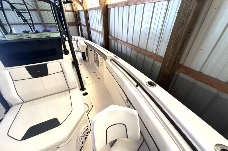  Yacht Photos Pics 2019 Wellcraft 302 Fisherman boat interior with white seating and storage, docked in a wooden shed.