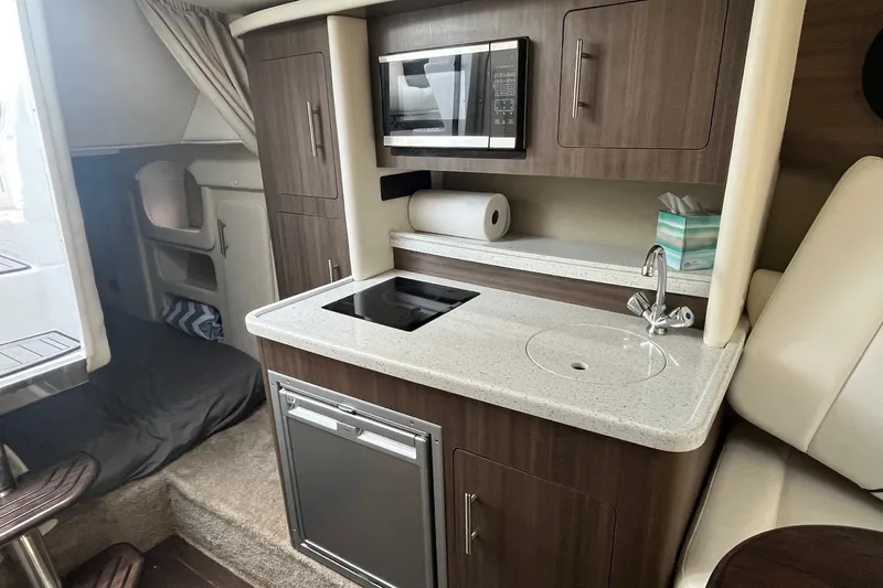  Yacht Photos Pics 2020 Rinker 290 EX boat interior with kitchenette, featuring microwave, sink, and storage cabinets.