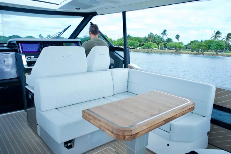 Sierra Tango VI Yacht Photos Pics 2025 Saxdor 400 GTO interior with white seating and wooden table, overlooking serene water.