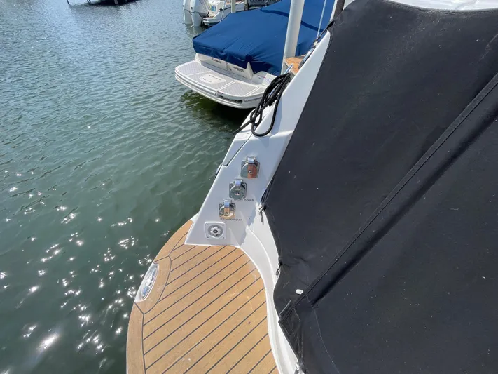  Yacht Photos Pics 2013 Rinker 310 Express Cruiser with wooden deck and black cover, docked on calm water.