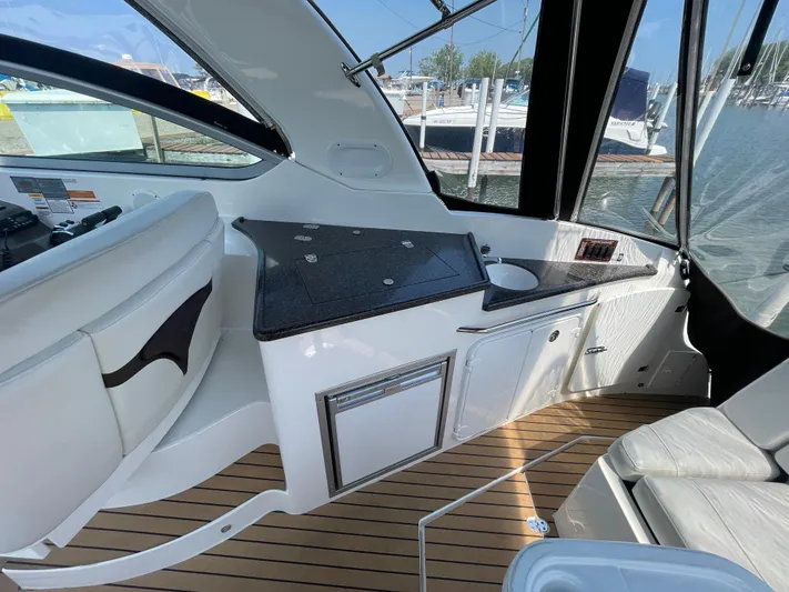 Yacht Photos Pics 2013 Rinker 310 Express Cruiser interior with kitchenette and seating, docked at marina.