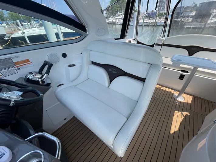  Yacht Photos Pics 2013 Rinker 310 Express Cruiser cockpit with white seating and wood flooring, docked at marina.