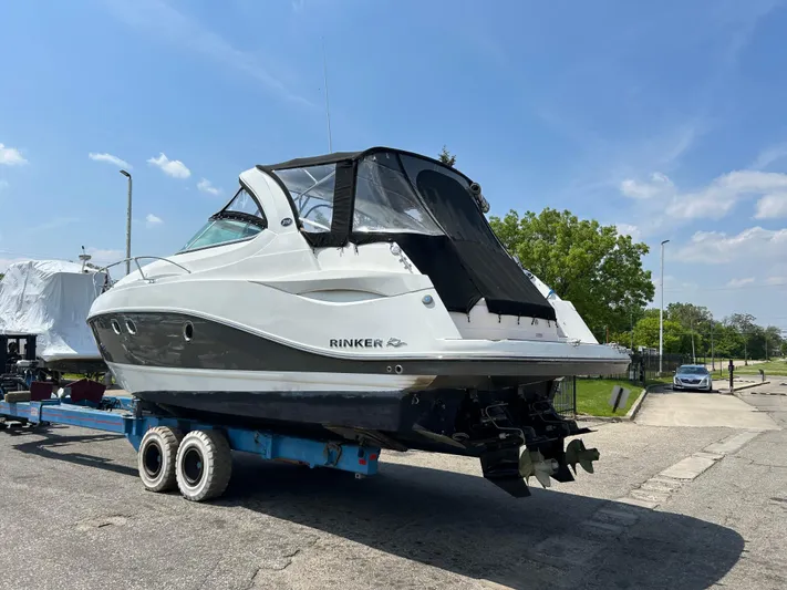  Yacht Photos Pics 2013 Rinker 310 Express Cruiser on trailer, parked outdoors under a clear blue sky.