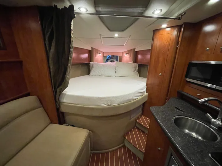  Yacht Photos Pics Interior of 2013 Rinker 310 Express Cruiser with bed, kitchenette, and seating area.
