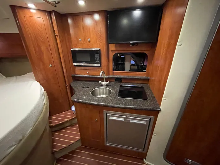  Yacht Photos Pics 2013 Rinker 310 Express Cruiser interior with kitchenette, featuring microwave, sink, and cooktop.