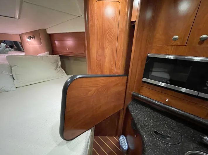  Yacht Photos Pics 2013 Rinker 310 Express Cruiser interior with bed, wooden cabinetry, and microwave.