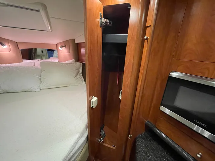  Yacht Photos Pics 2013 Rinker 310 Express Cruiser interior with bed, wooden cabinetry, and microwave.
