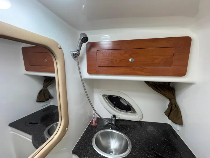  Yacht Photos Pics 2013 Rinker 310 Express Cruiser bathroom with sink, mirror, and wooden cabinet.