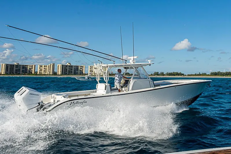 Quest Yacht Photos Pics 2011 Yellowfin 39 Offshore boat cruising on blue ocean near coastal buildings.
