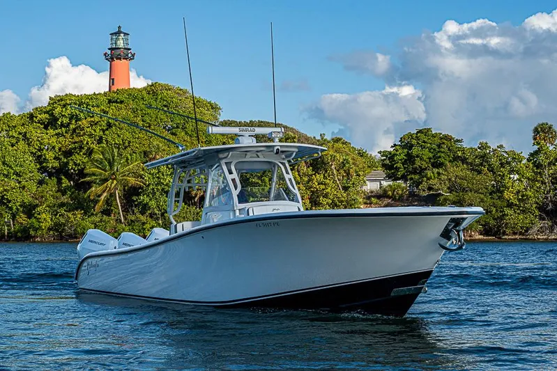 Quest Yacht Photos Pics 2011 Yellowfin 39 Offshore boat cruising near a lush island with a lighthouse.
