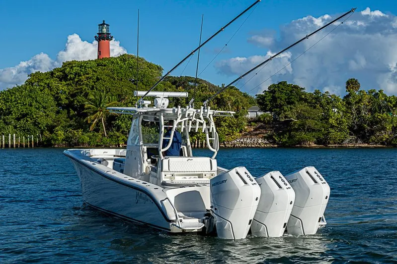 Quest Yacht Photos Pics 2011 Yellowfin 39 Offshore boat with triple Mercury engines near a lighthouse.