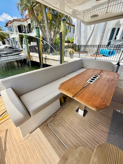 La Vida Boca Yacht Photos Pics Luxury seating area on 2019 Sealine F430 yacht, featuring a wooden table and waterfront view.