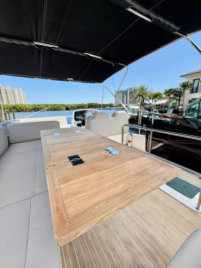 La Vida Boca Yacht Photos Pics 2019 Sealine F430 yacht deck with wooden table, under canopy, overlooking waterfront and buildings.