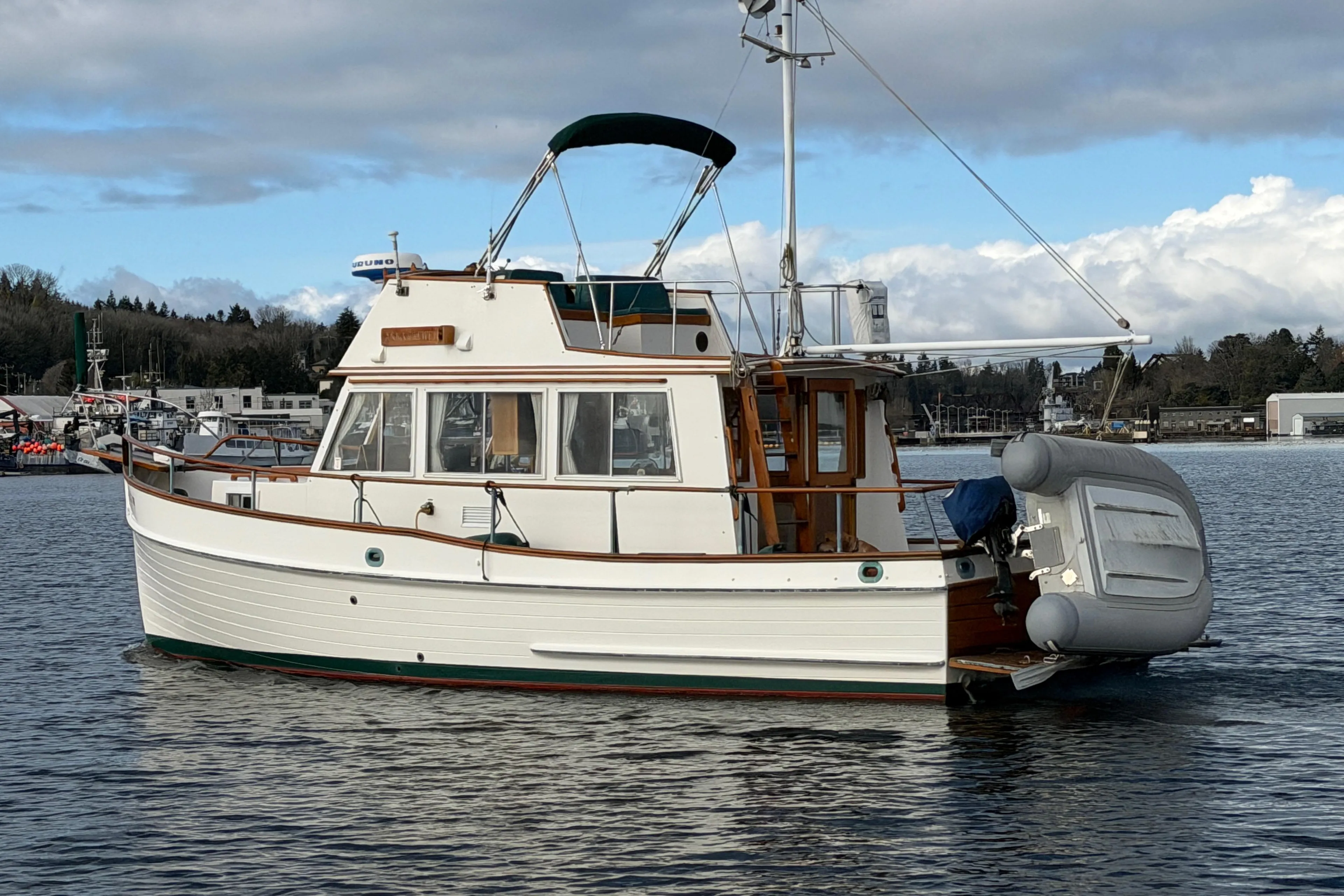 1981 Grand Banks 32 Sedan boat on calm water, featuring classic design and inflatable dinghy.
