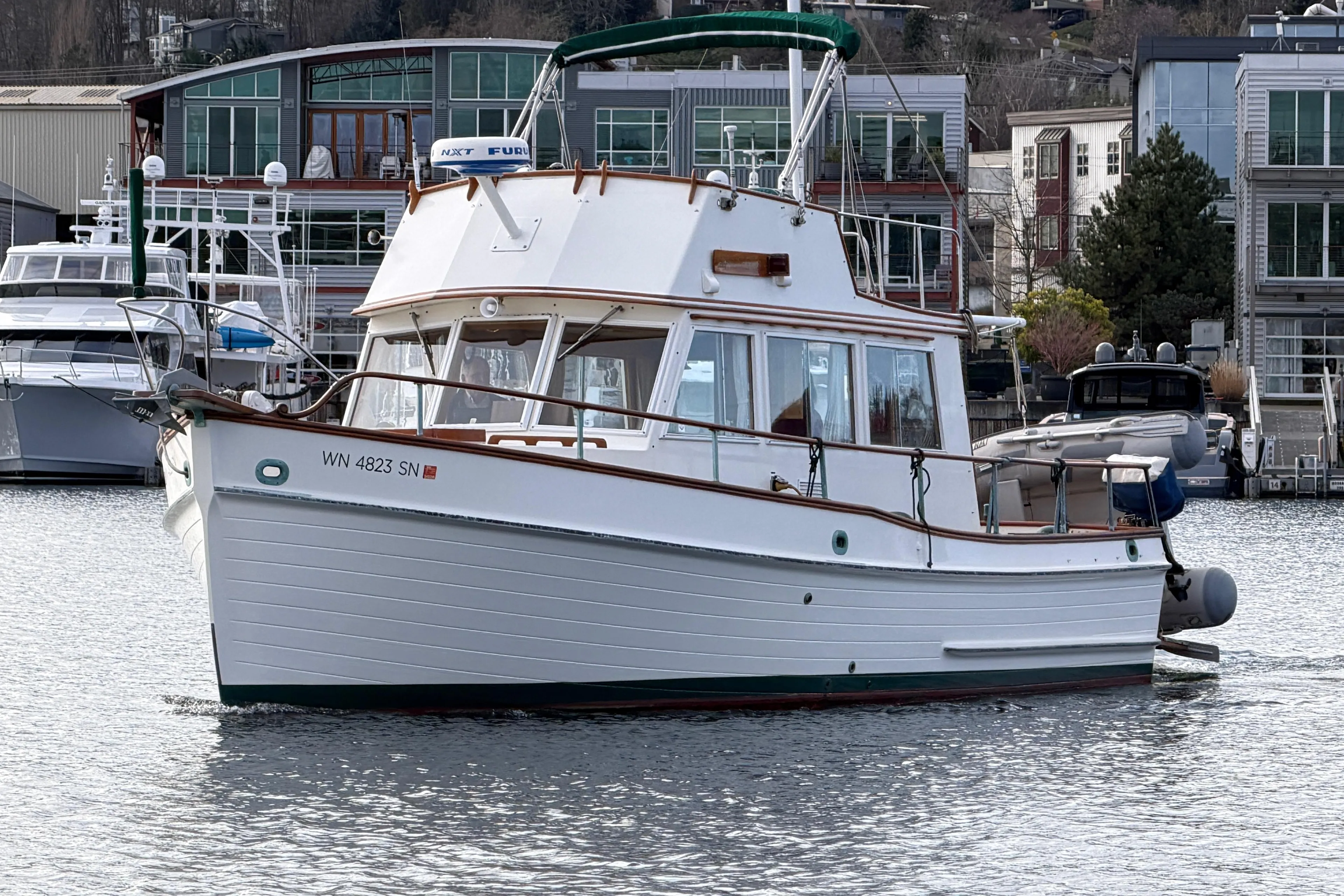 1981 Grand Banks 32 Sedan boat docked in a marina, surrounded by modern buildings.