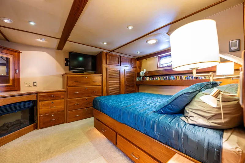 Traveller II Yacht Photos Pics Luxurious 2001 Rodriquez Pilothouse yacht bedroom with wood furnishings and cozy lighting.