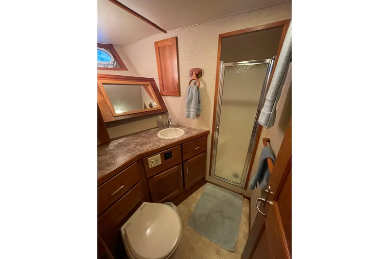 Traveller II Yacht Photos Pics 2001 Rodriquez Pilothouse bathroom with shower, sink, and wooden cabinetry.