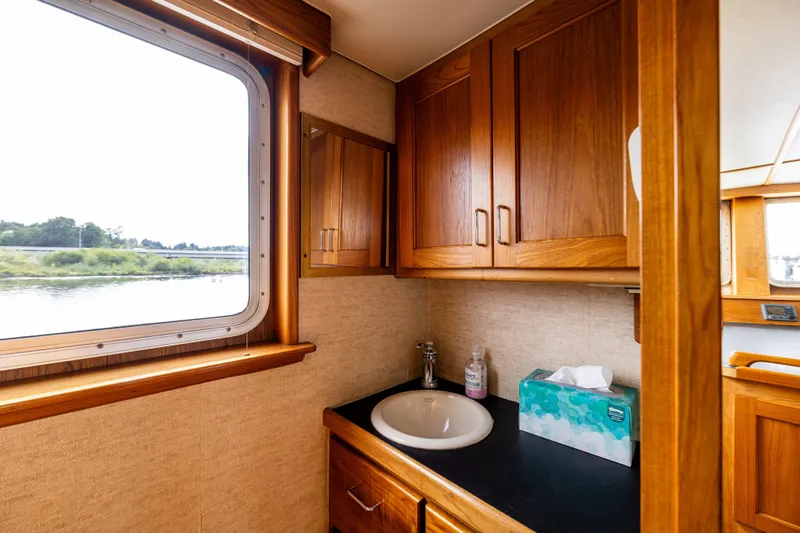 Traveller II Yacht Photos Pics 2001 Rodriquez Pilothouse bathroom with wooden cabinets and river view.