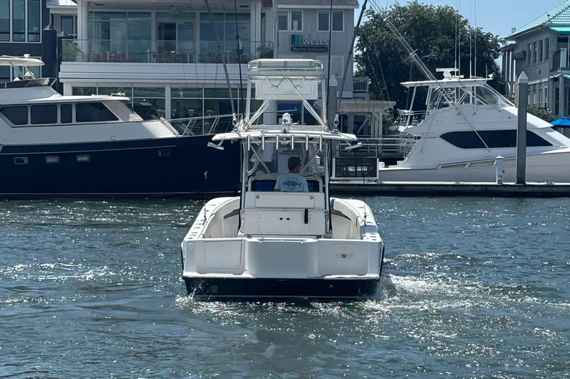  Yacht Photos Pics 2004 SeaVee 34 boat navigating marina waters, surrounded by yachts and waterfront buildings.