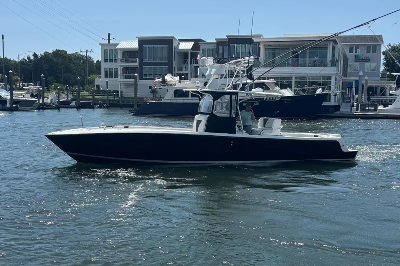  Yacht Photos Pics 2004 SeaVee 34 boat cruising on a sunny day near modern waterfront buildings.