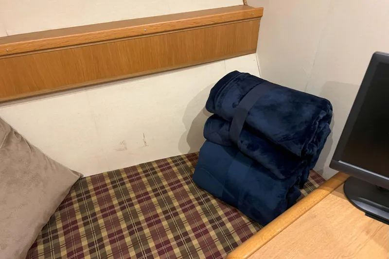 Dream Catcher Yacht Photos Pics Cozy cabin interior with plaid bedding and folded navy blankets on a West Bay 58 yacht.