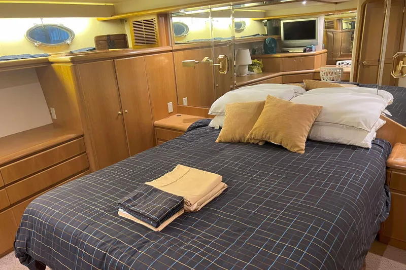 Dream Catcher Yacht Photos Pics Luxurious bedroom interior of 1998 West Bay 58 yacht with cozy bedding and wooden cabinetry.
