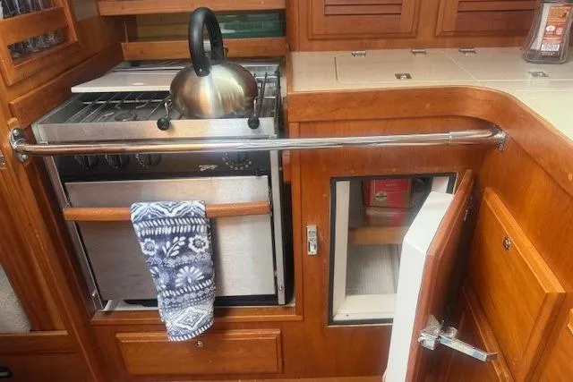 Midnight Yacht Photos Pics 2005 Sabre 386 yacht kitchen with stove, kettle, and wooden cabinetry.