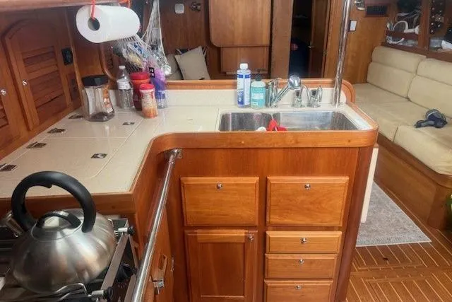 Midnight Yacht Photos Pics 2005 Sabre 386 yacht interior kitchen with wooden cabinetry and stainless steel sink.