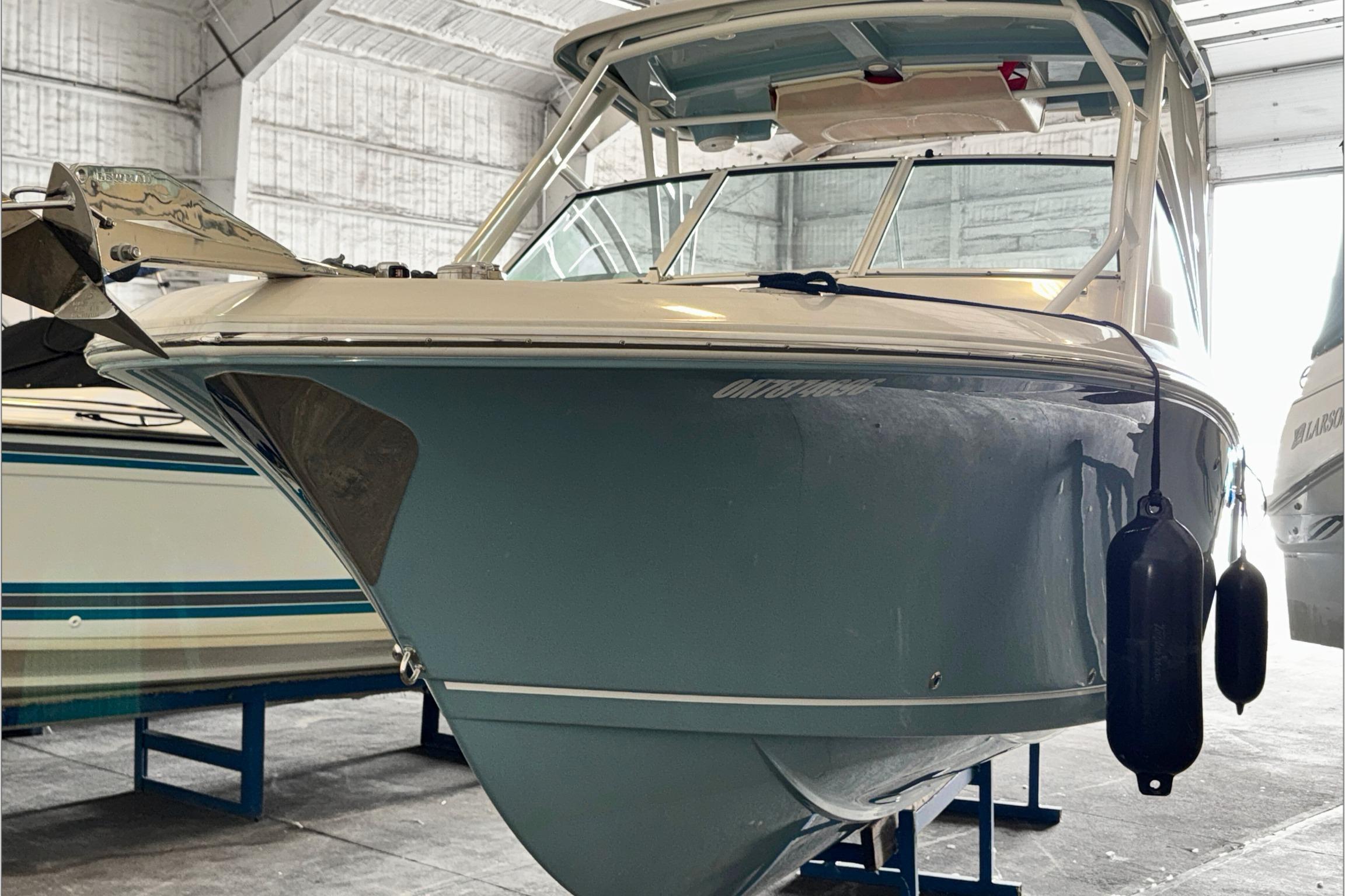 2021 Sailfish 245 DC boat in storage, featuring a sleek blue hull and protective fenders.