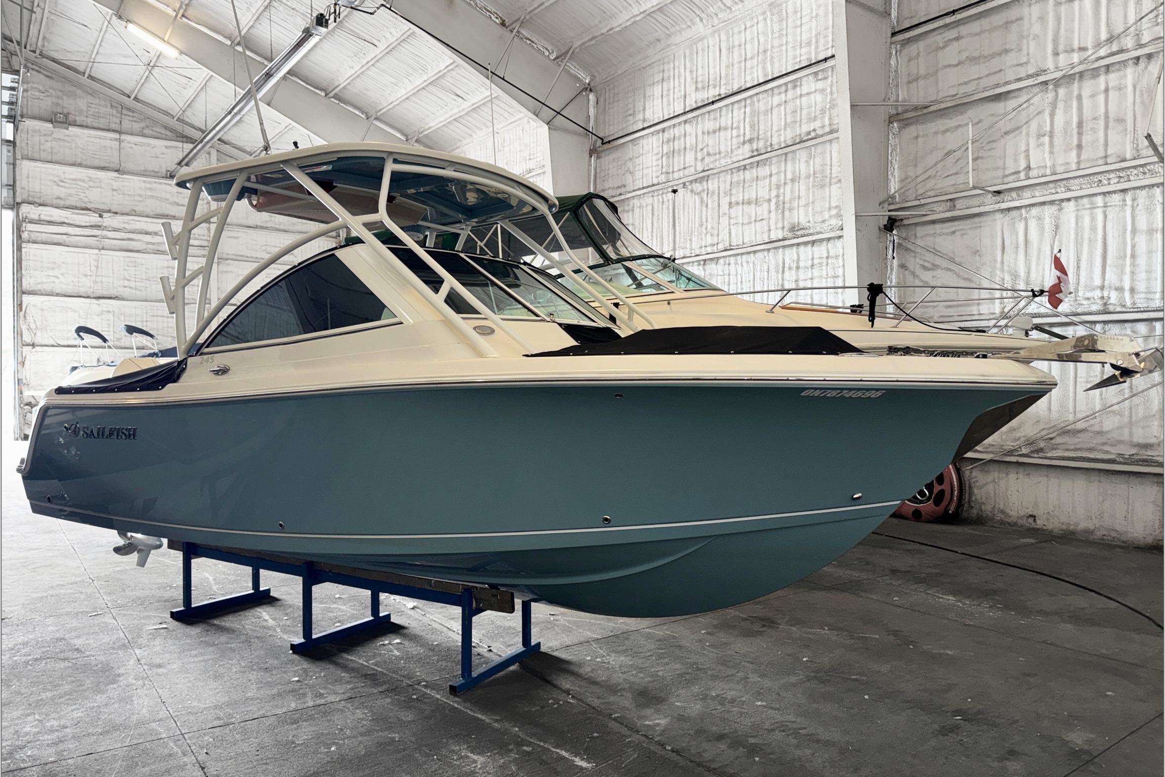 2021 Sailfish 245 DC boat in a warehouse, showcasing sleek design and blue hull.