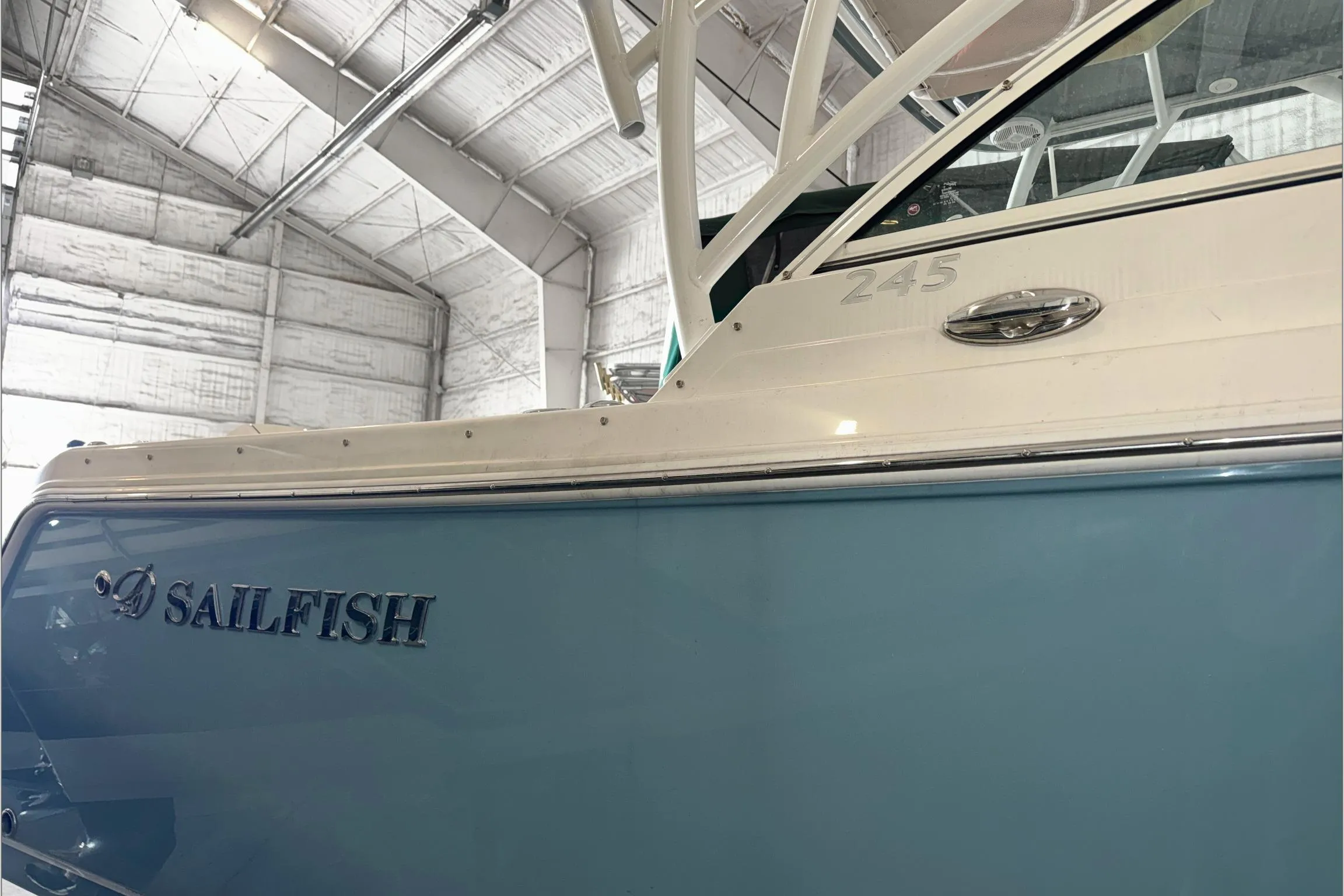 2021 Sailfish 245 DC boat in a warehouse, showcasing sleek design and branding.