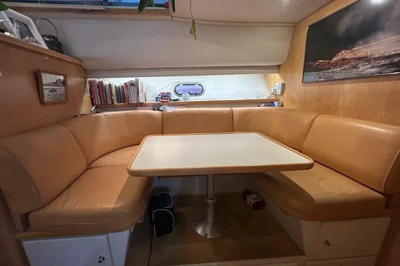 Contentment Yacht Photos Pics 1995 Carver 440 Aft Cabin Motor Yacht interior with cozy dining area and bookshelves.