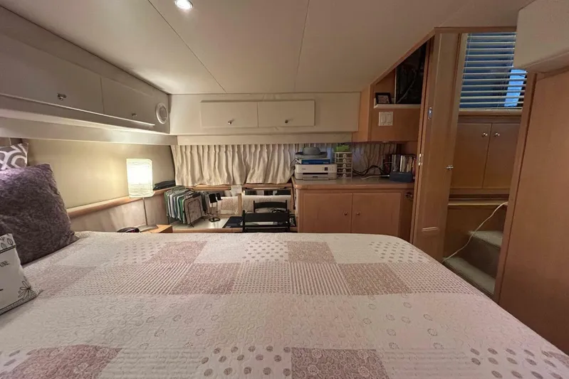Contentment Yacht Photos Pics Cozy bedroom in 1995 Carver 440 Aft Cabin Motor Yacht with quilted bedding and wooden cabinetry.