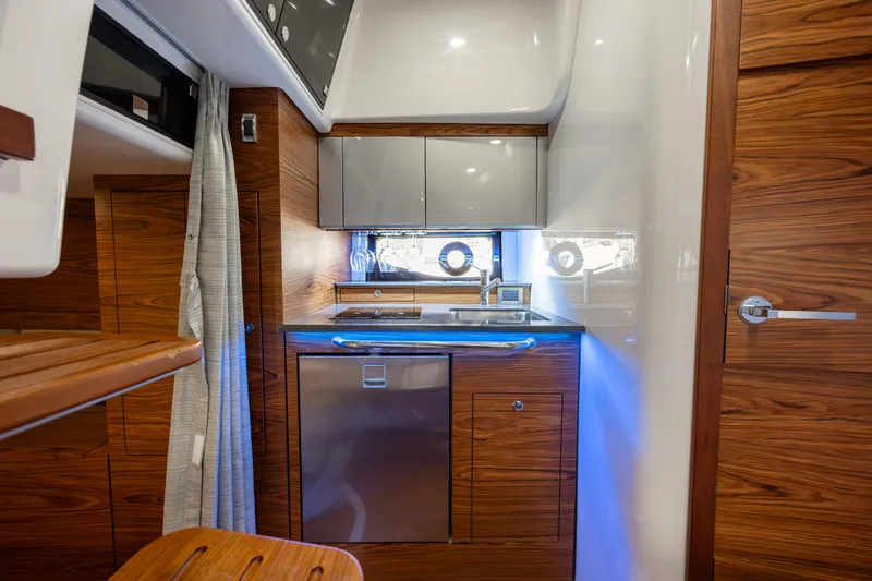 New Trade-in- All Offers & Trades Welcome Yacht Photos Pics 2021 Boston Whaler 405 Conquest interior kitchen with modern wood cabinetry and stainless steel appliances.