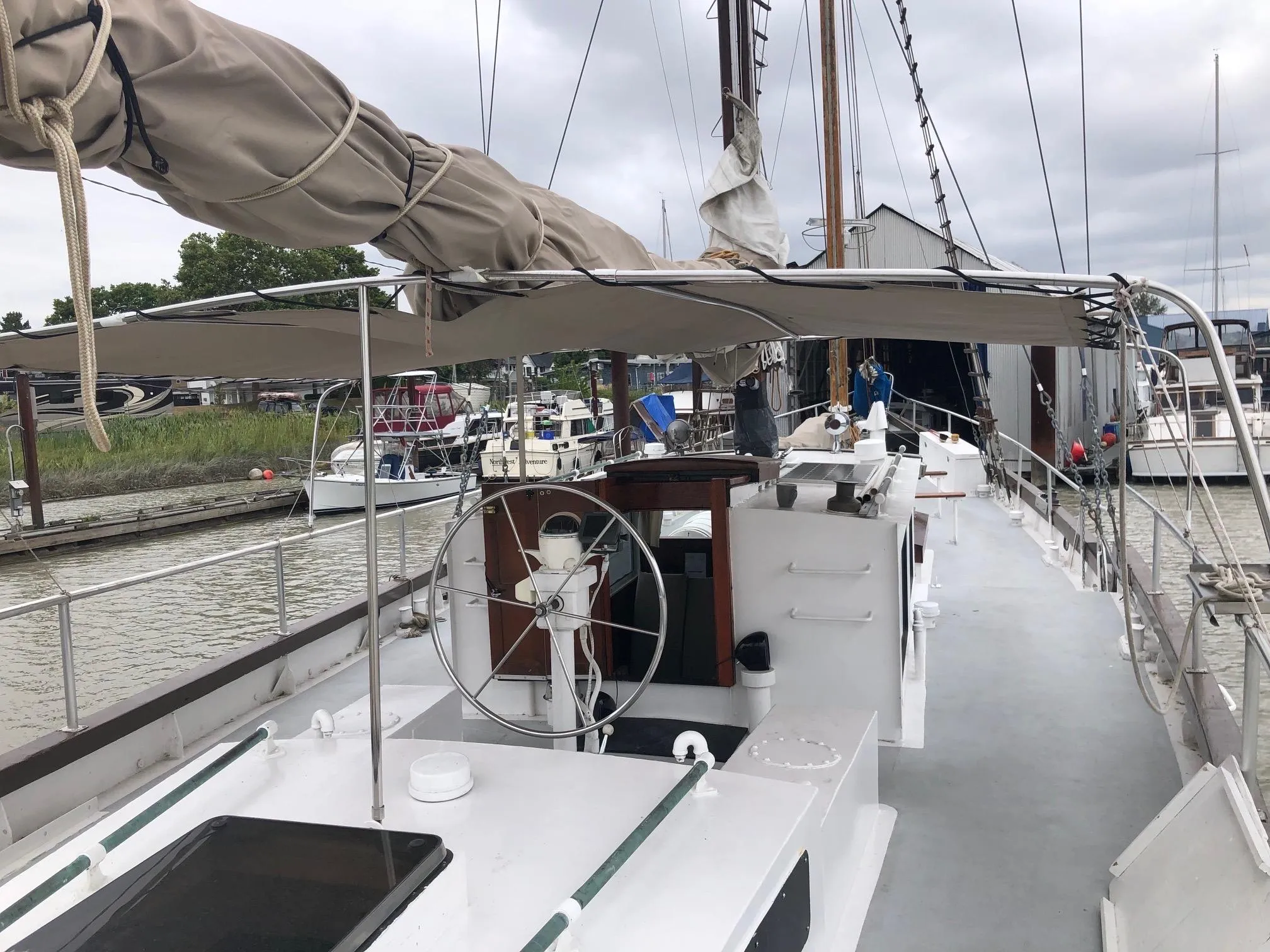 1975 Custom Staysail Schooner docked at marina, featuring deck and steering wheel.
