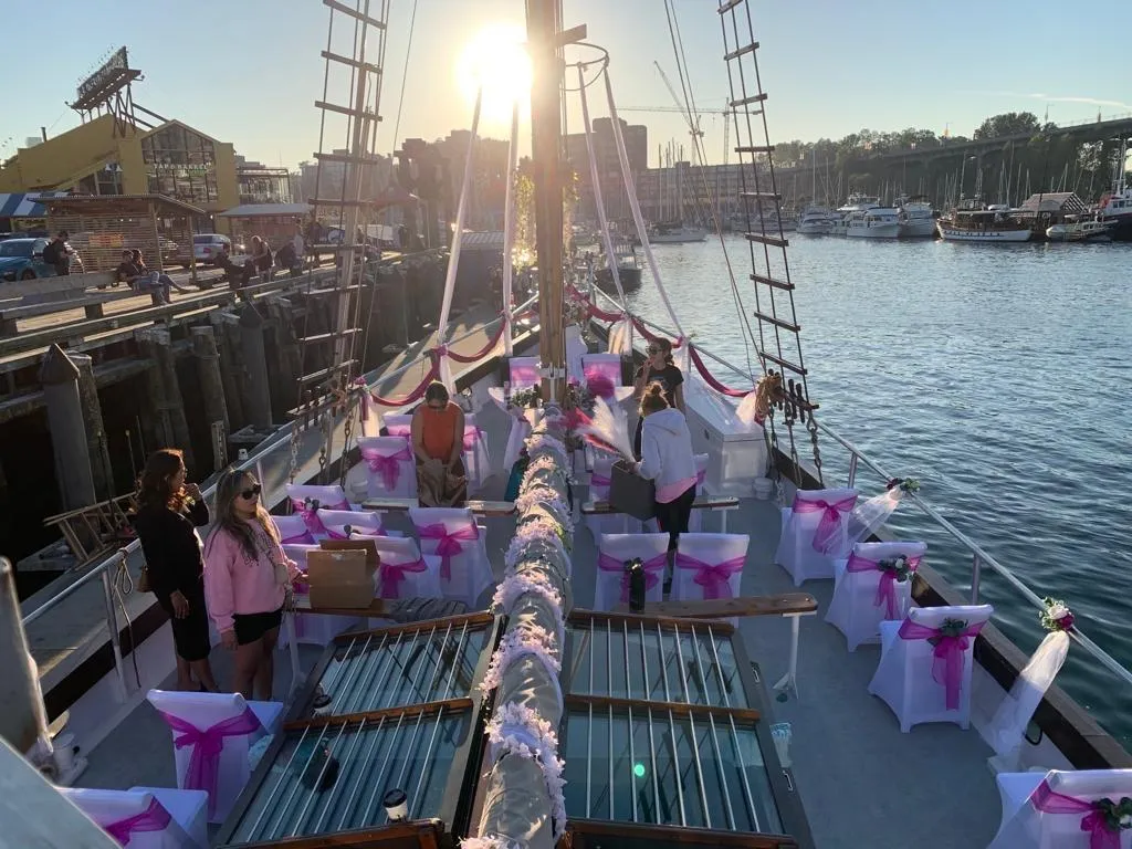 Staysail schooner deck decorated for an event, with pink and white accents, at sunset.