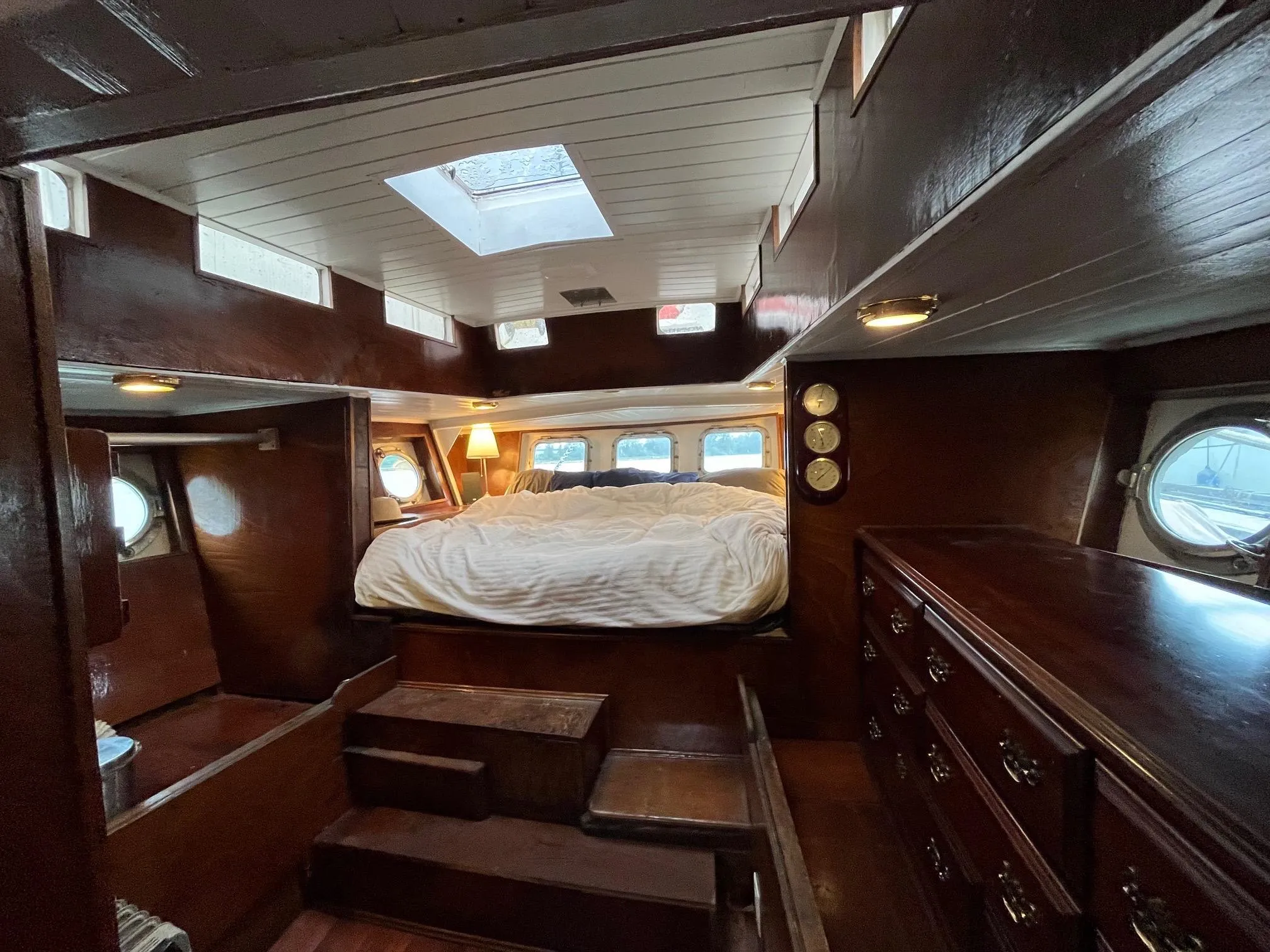 Cozy cabin interior of a 1975 Custom Staysail Schooner with wooden furnishings and skylight.