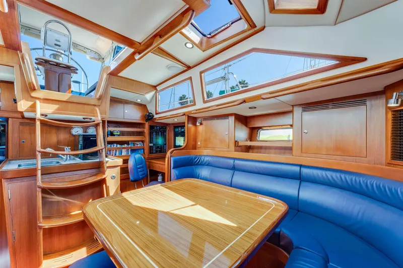 Liberte' Yacht Photos Pics Luxurious interior of 2011 Hylas 46 yacht with wood finish and blue seating.