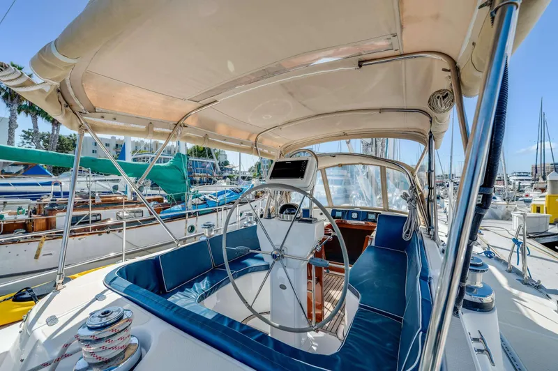 Liberte' Yacht Photos Pics 2011 Hylas 46 yacht cockpit with blue seating and steering wheel in marina.