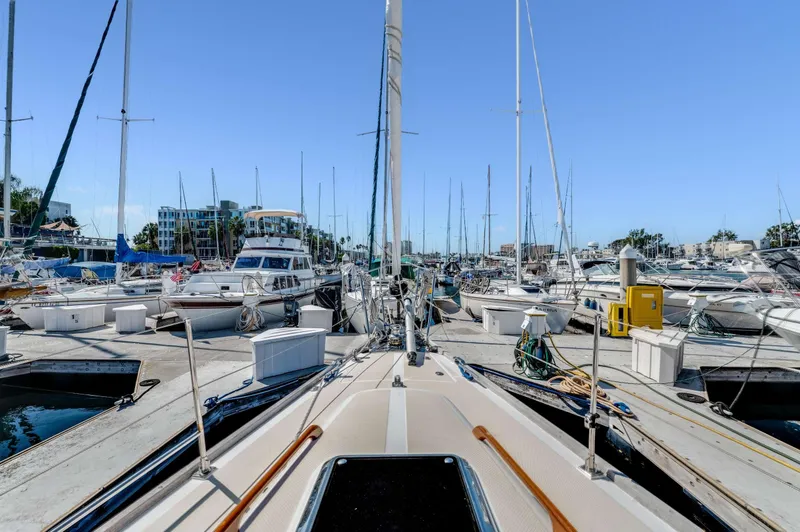 Liberte' Yacht Photos Pics Hylas 46 sailboat docked in a marina, surrounded by other boats, clear blue sky.