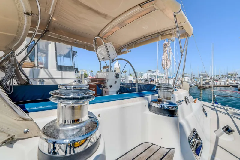 Liberte' Yacht Photos Pics 2011 Hylas 46 yacht cockpit with marina view, featuring steering wheel and winches.