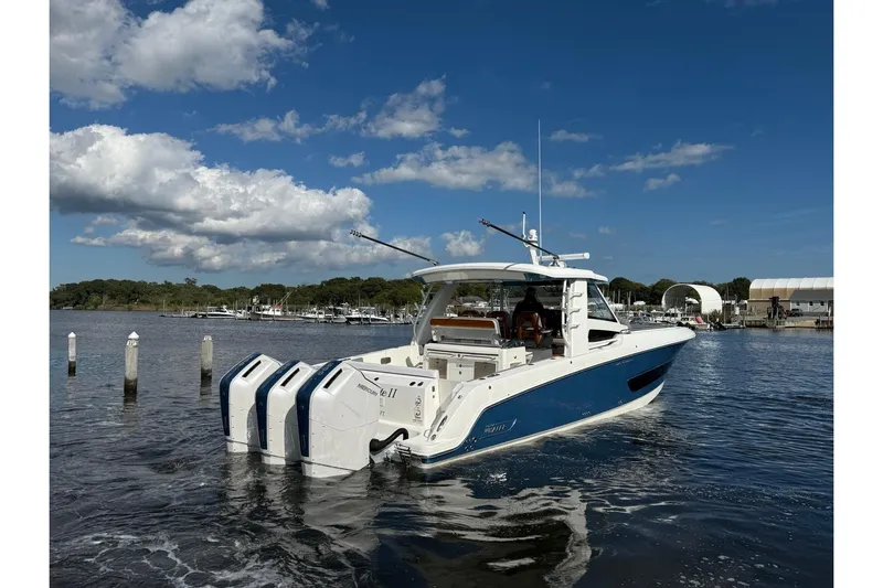  Yacht Photos Pics 2024 Boston Whaler 420 Outrage boat on water, featuring triple engines, under a clear blue sky.